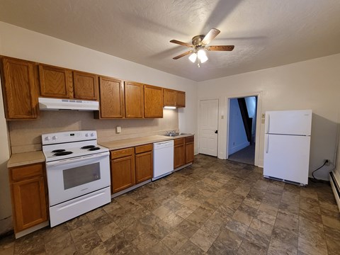 A kitchen with white appliances and wooden cabinets.