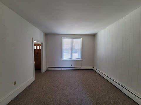 A room with a carpeted floor and a window.