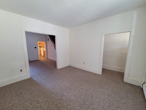 A room with a carpeted floor and a doorway leading to another room.