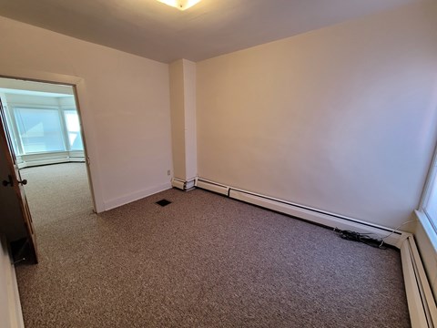 A room with a carpeted floor and a window.