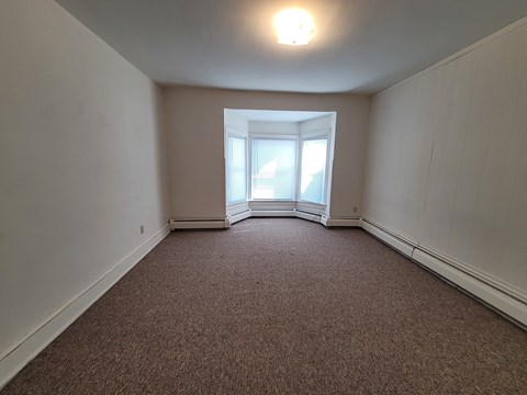 A room with a carpeted floor and a window.