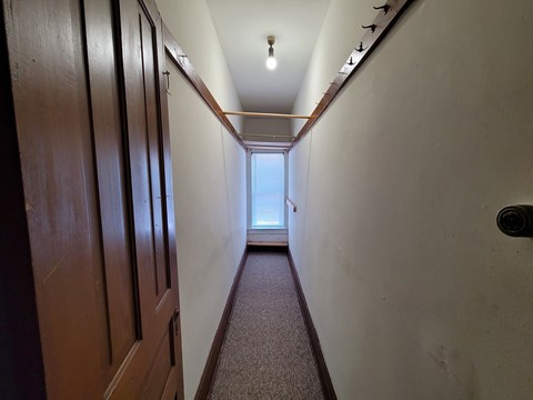 A long hallway with a carpeted floor and wooden doors on the left.