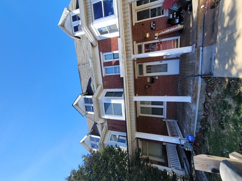 A tall building with a red brick facade and white trim around the windows.