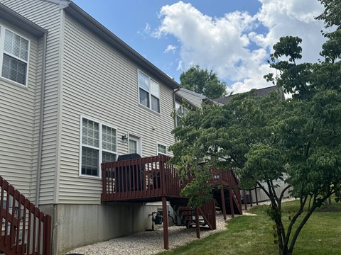 A house with a deck and a tree in front.