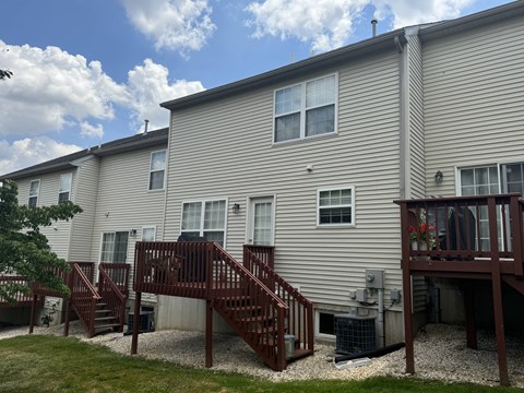 A beige building with a brown deck and stairs.
