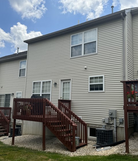 A house with a grey siding and a brown deck.