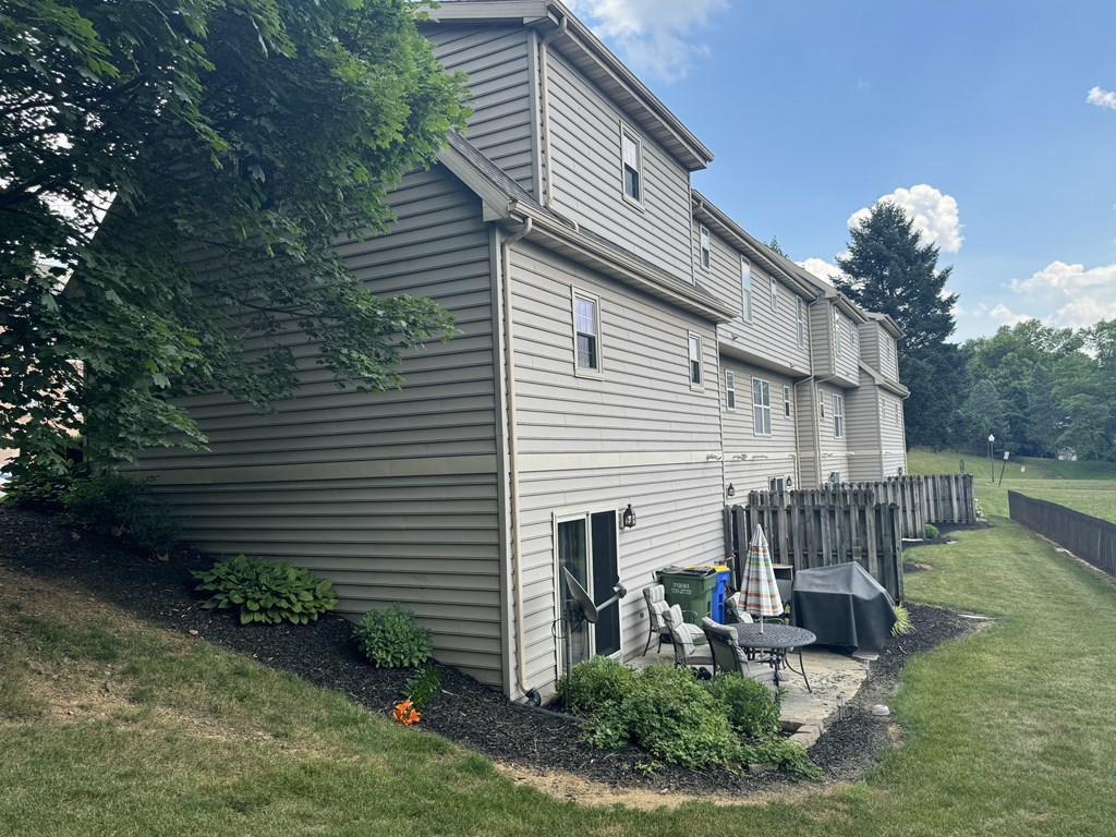 A grey building with a patio and a tree in front.