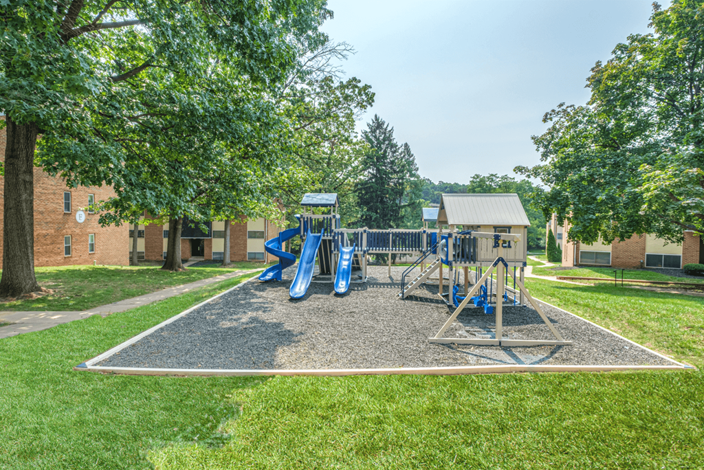 A playground with a blue slide and a grey sandbox.