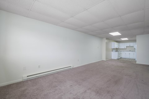 A large empty room with carpeted floor and white walls.