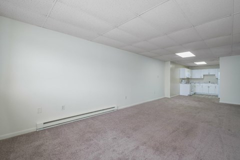 A large empty room with carpeted floor and white walls.