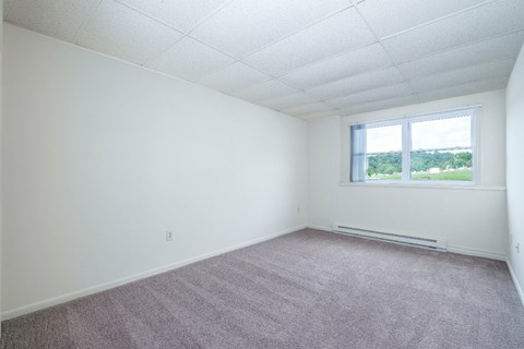 A room with a window and carpeted floor.