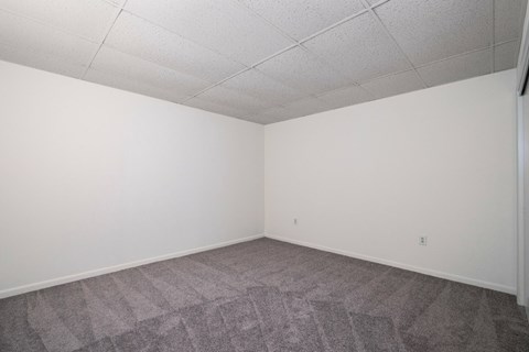 A room with a grey carpet and white walls.