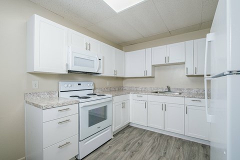 A kitchen with white appliances and cabinets.