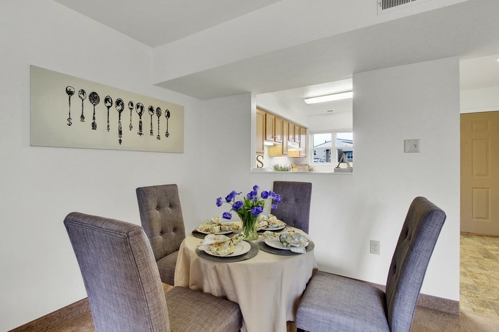 A dining room with a table set for two and a key artwork on the wall.