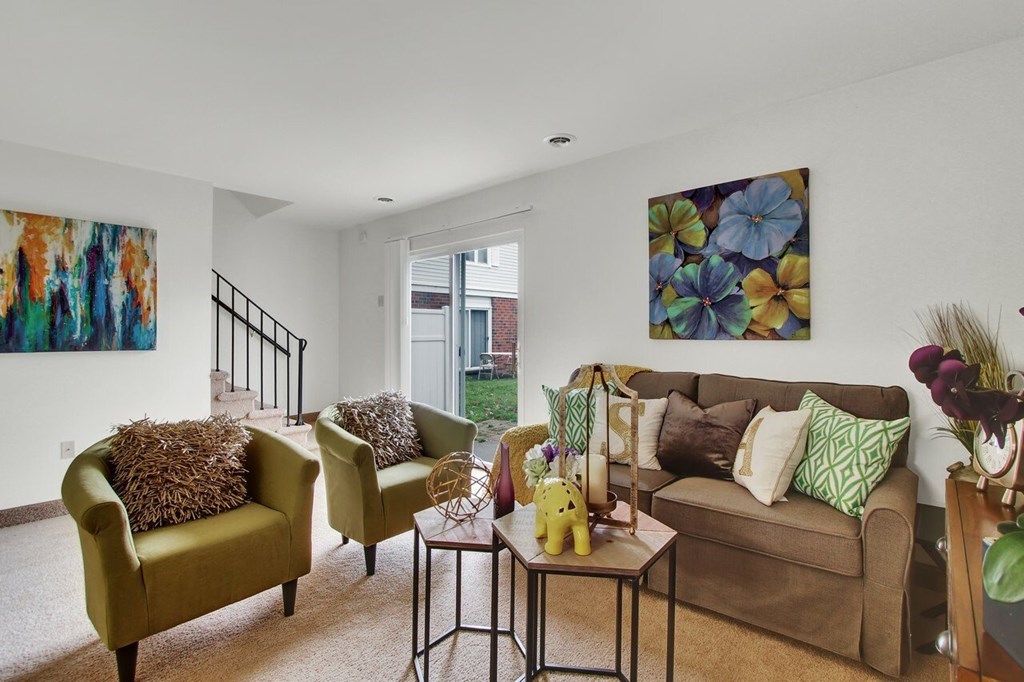 A living room with a green chair, a brown couch, and a painting on the wall.