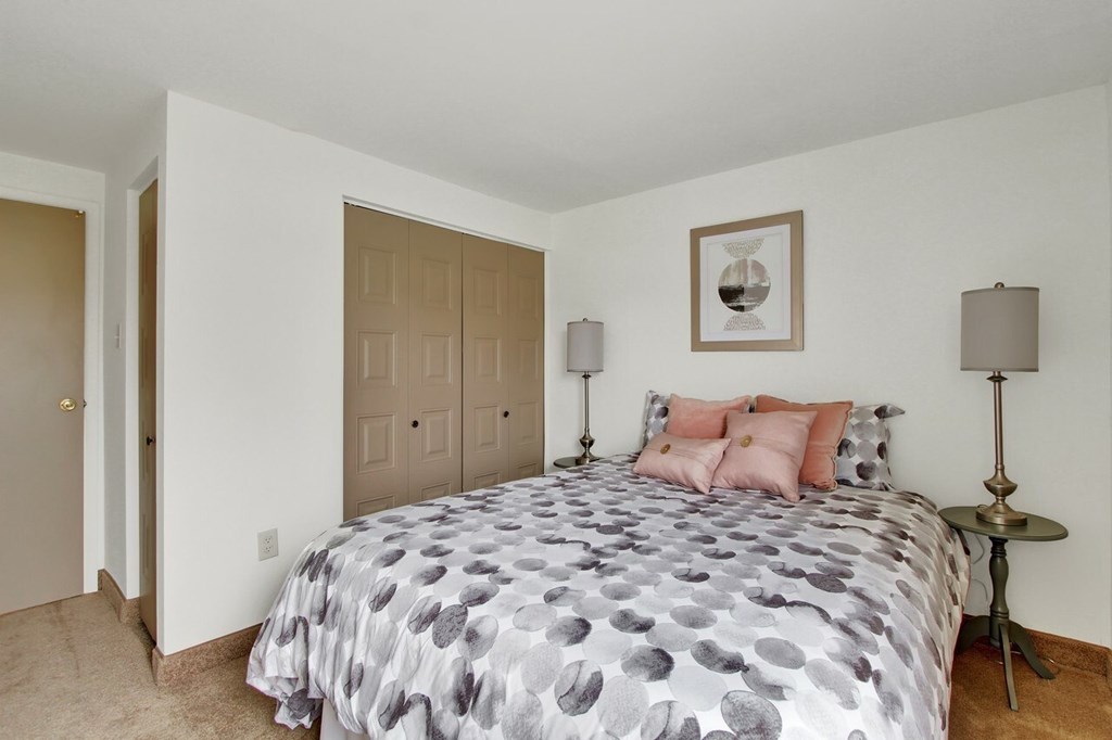 A bedroom with a bed, two lamps, and a picture on the wall.