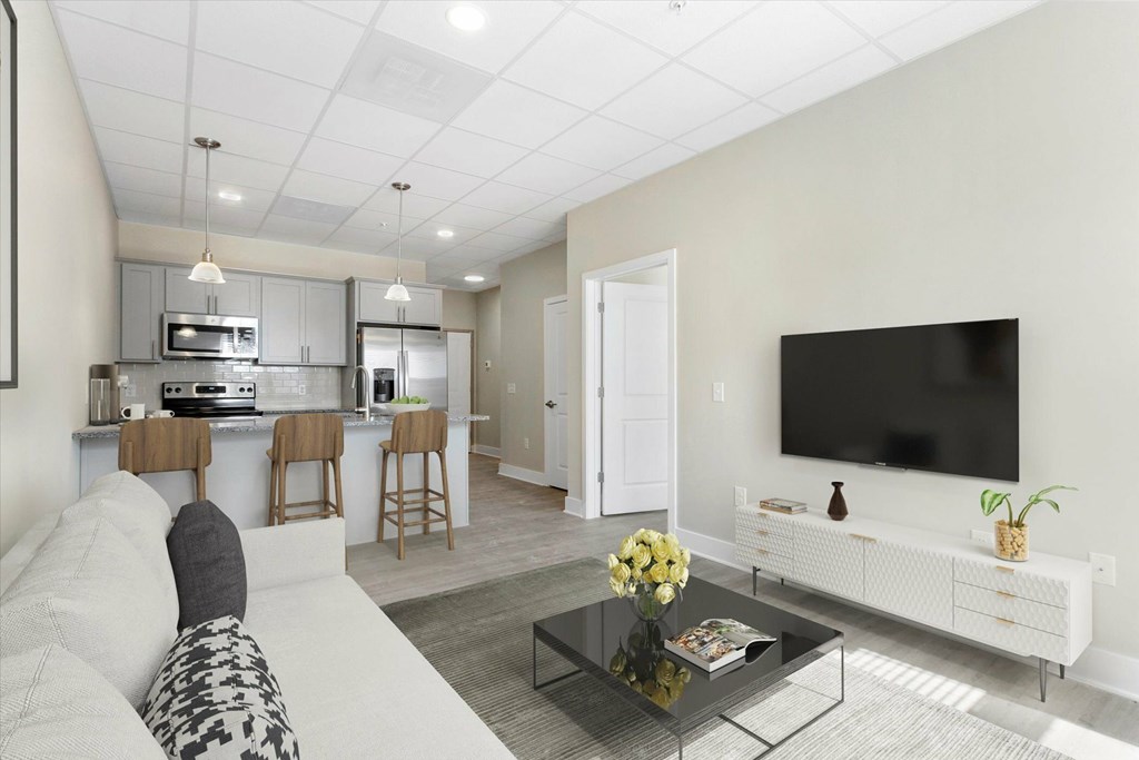 A modern living room with a white couch, a black coffee table, and a flat-screen TV mounted on the wall.