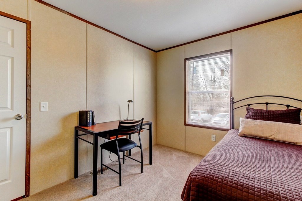A bedroom with a bed, desk, and chair.