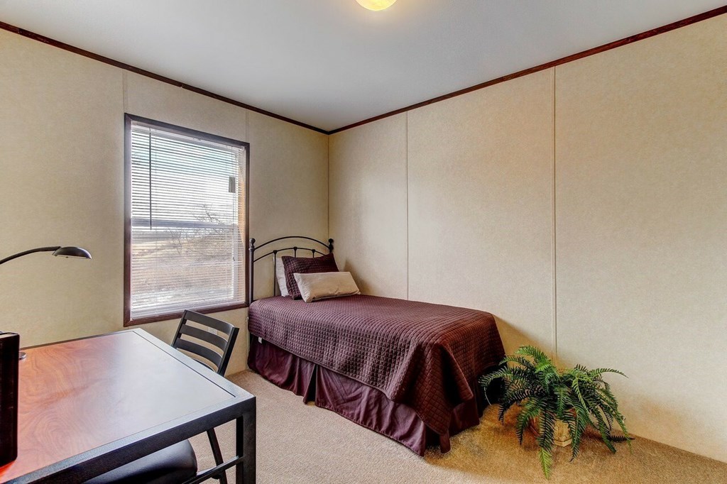 A room with a bed, a table and a chair.