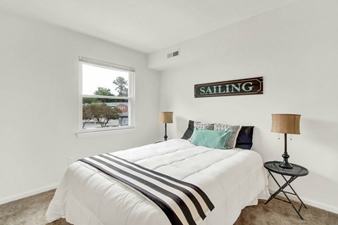 A bedroom with a bed, two lamps, and a sign that says "SAILING".