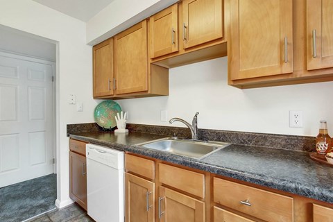 A kitchen with wooden cabinets and a white dishwasher.