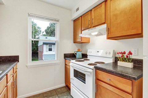 A kitchen with wooden cabinets and a white stove top oven.