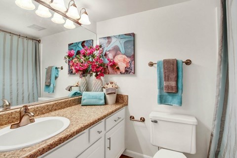 A bathroom with a white toilet, a sink, and a painting of flowers on the wall.