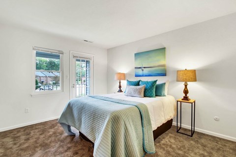 A bedroom with a bed, two lamps, and a painting on the wall.