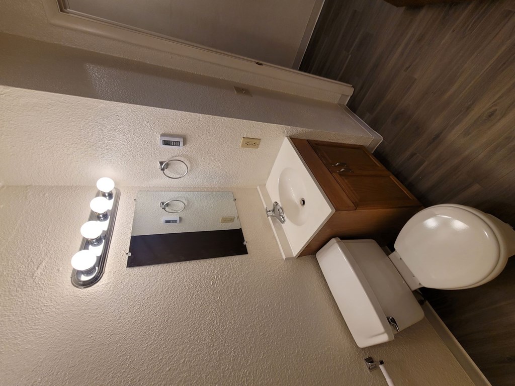 A bathroom with a toilet, sink, and lights.