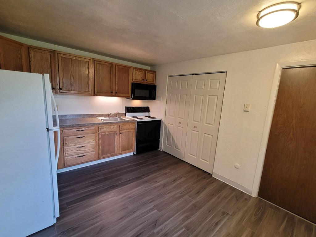 A kitchen with a white refrigerator and wooden cabinets.