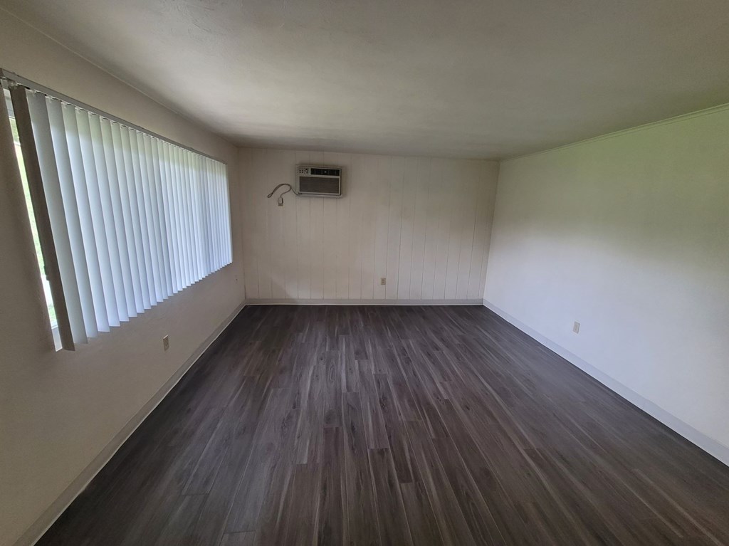 A room with wooden flooring and a window with blinds.