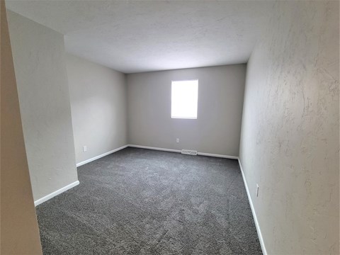 A room with a carpeted floor and a window.