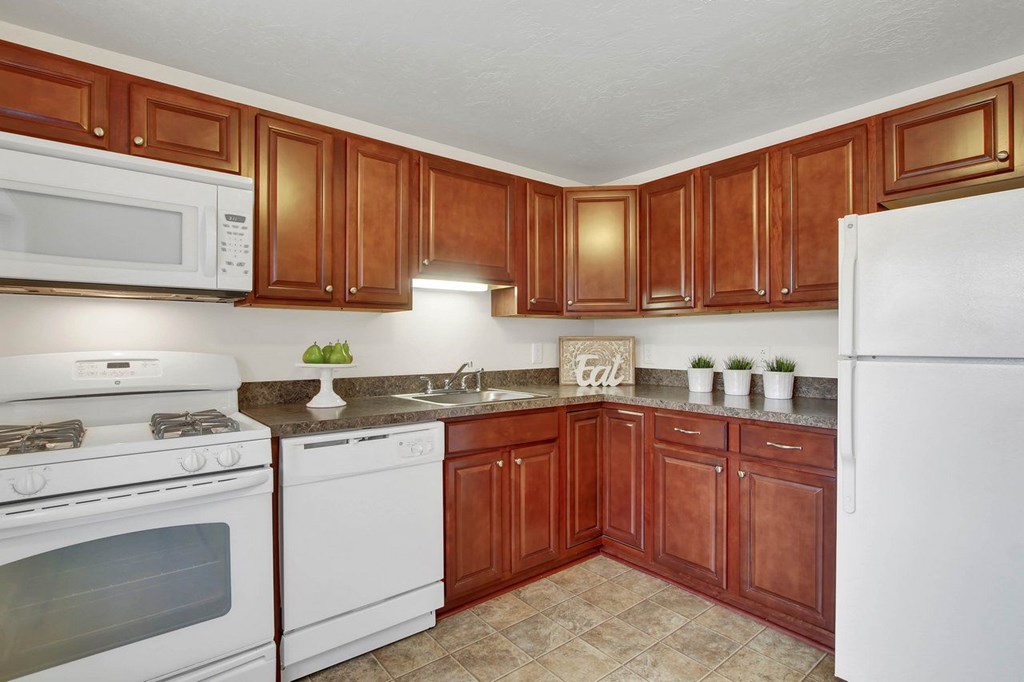 A kitchen with brown cabinets and white appliances.
