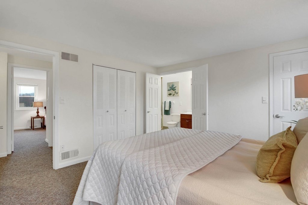 A bedroom with a large bed and a carpeted floor.