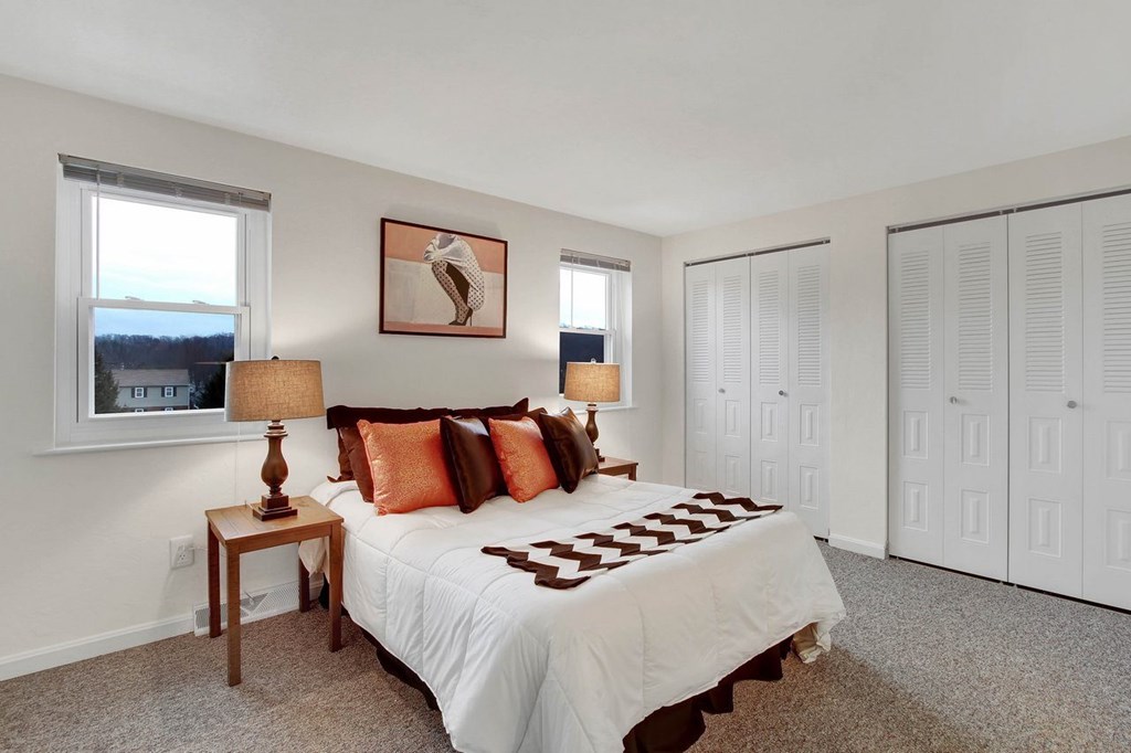 A bedroom with a bed, two lamps, and a painting on the wall.