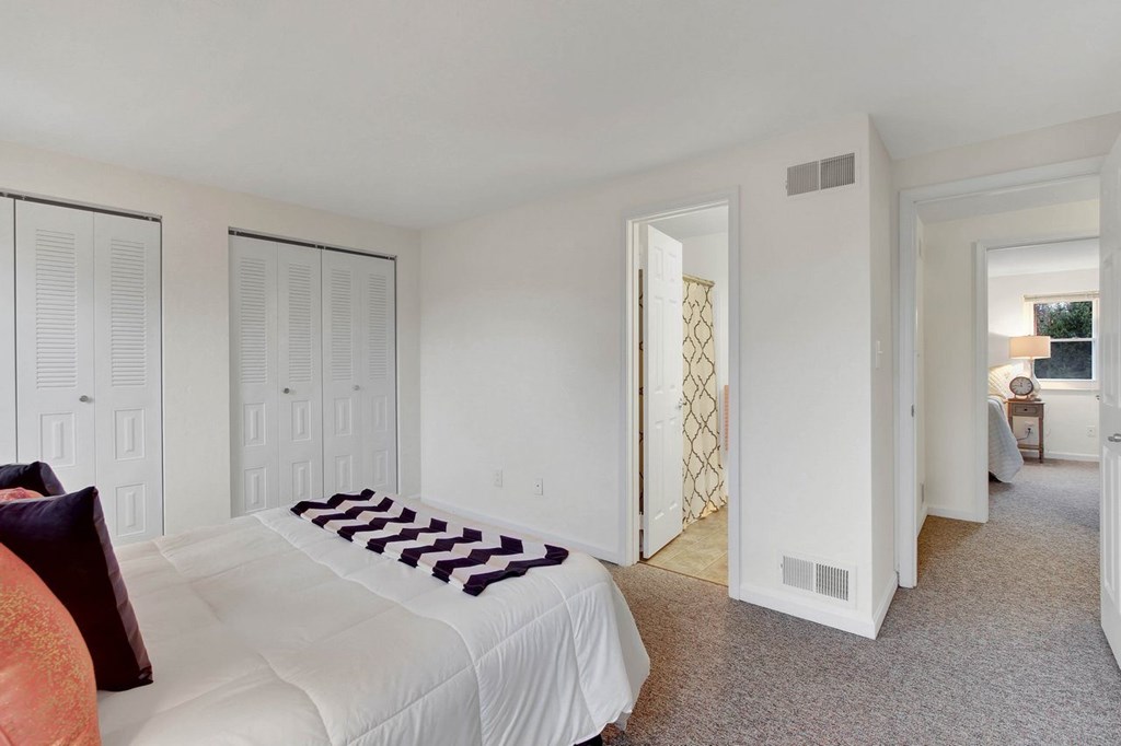 A bedroom with a white bed and a white wardrobe.