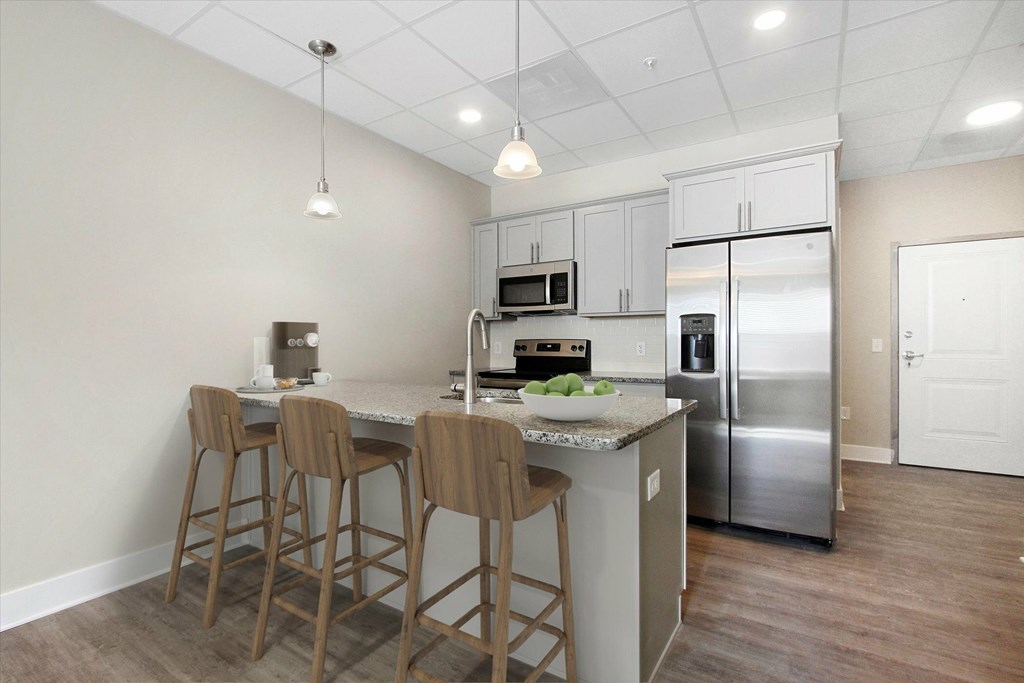 A kitchen with a refrigerator, microwave, oven, and sink.