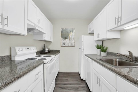 A kitchen with white cabinets and a granite countertop.