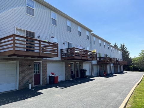 A long white building with a red door and a balcony.