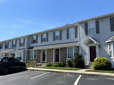 A black car is parked on the street in front of a row of houses.
