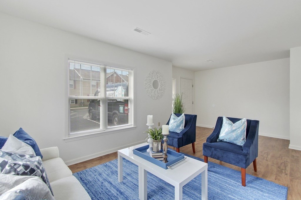 A living room with a white couch, blue chairs, and a white coffee table.
