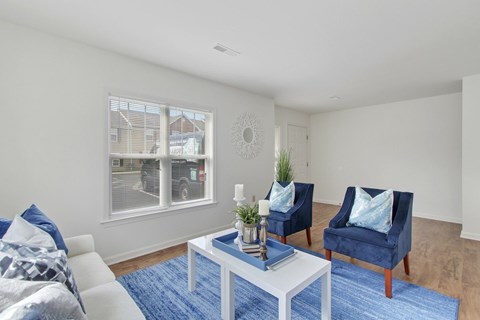 A living room with a white couch, blue chairs, and a white coffee table.