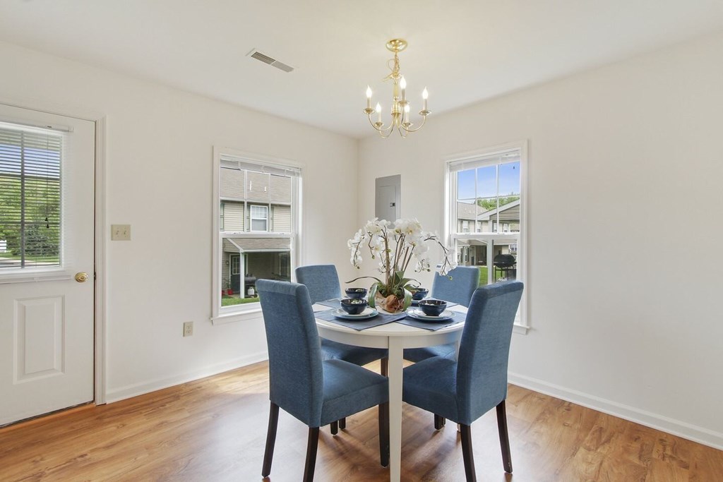 A dining room with a table set for two and a chandelier.