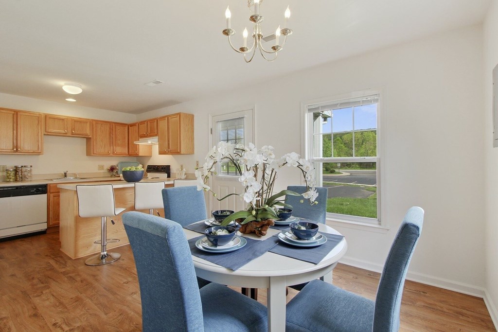 A dining room with a table set for two and a chandelier hanging from the ceiling.
