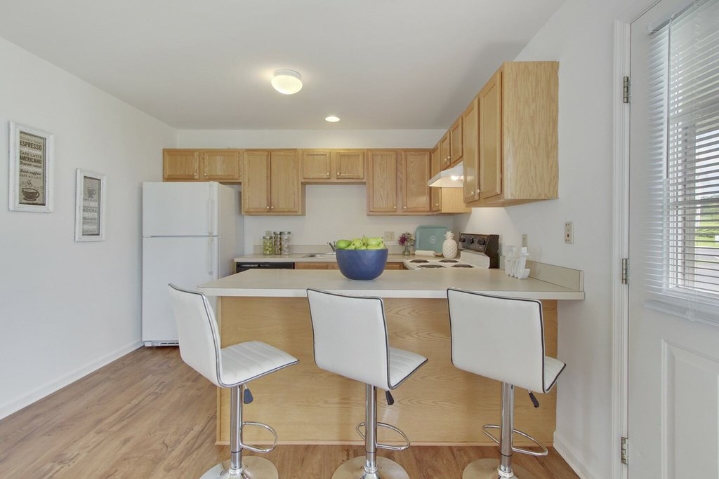 A kitchen with white chairs and a white fridge.