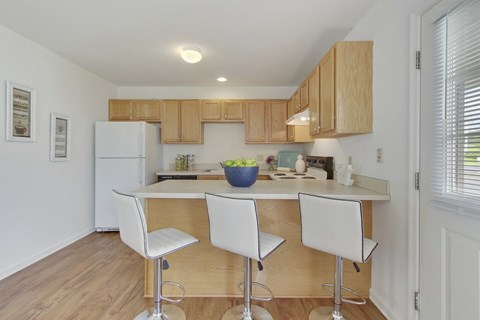 A kitchen with white chairs and a white fridge.