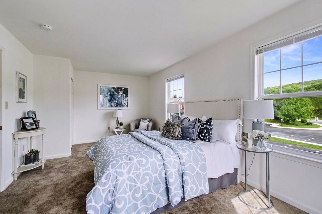A bedroom with a large bed and a window overlooking a green landscape.