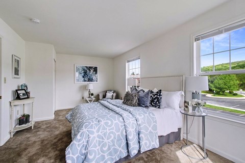 A bedroom with a large bed and a window overlooking a green landscape.