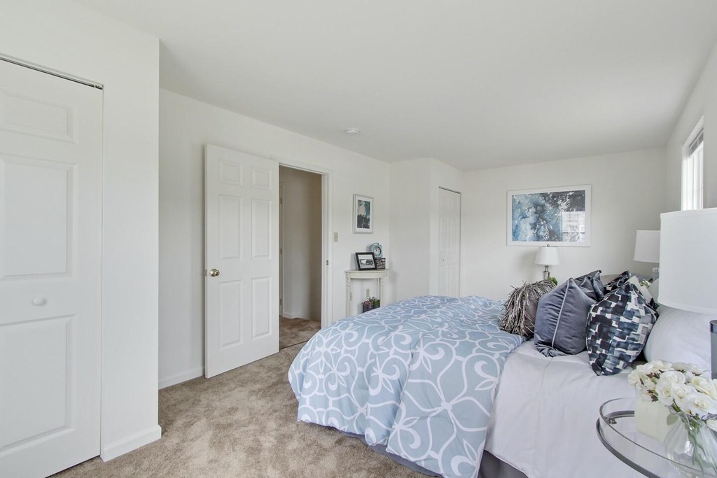 A bedroom with a bed, nightstand, and a painting on the wall.