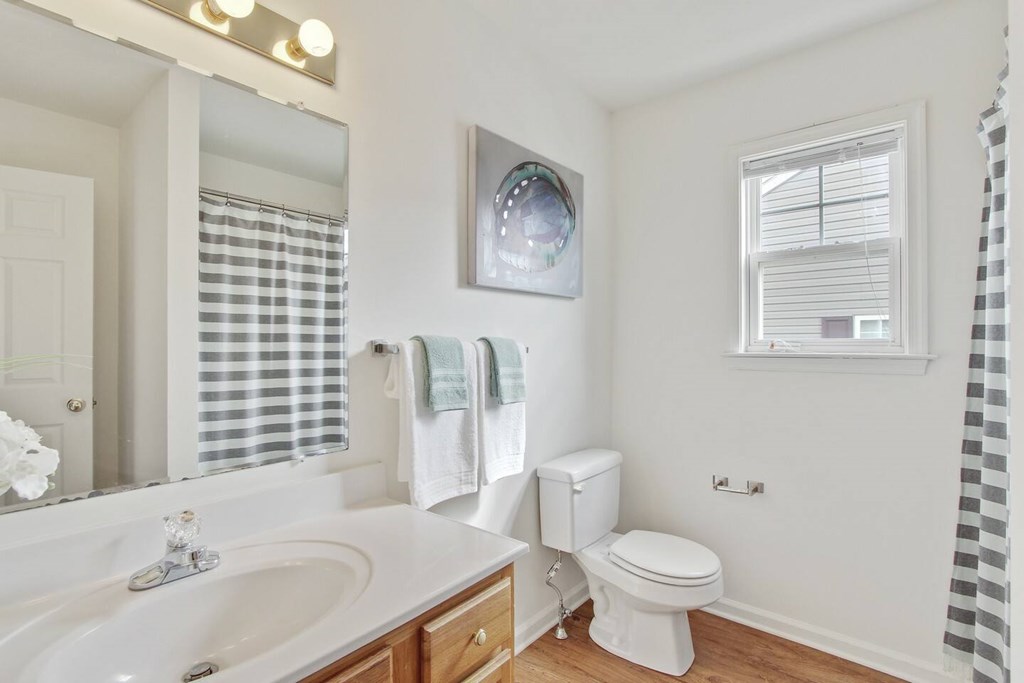 A bathroom with a toilet, sink, and mirror.
